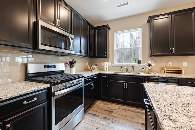 kitchen with black cabinets and salt and pepper granite counters